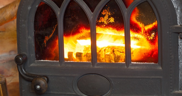en brasa brinner innanför ett fönster i en järnkamin