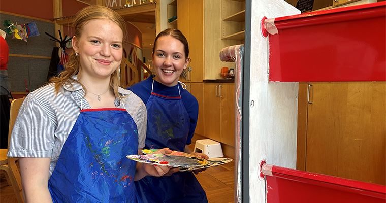 Elever från Härnösands gymnasium målar på en bokvagn. 