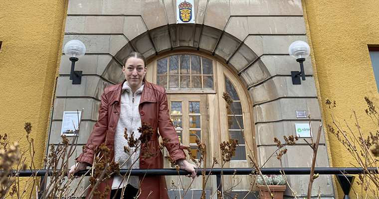 Kvinna som står framför entrén till en stor byggnad.