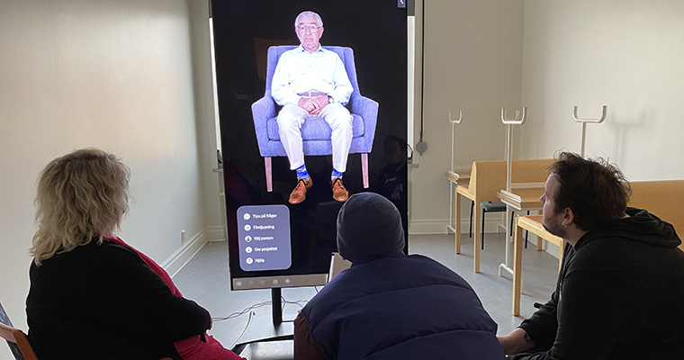 Besökare tittar på en skärm som visade inspelade intervjuer med en person.