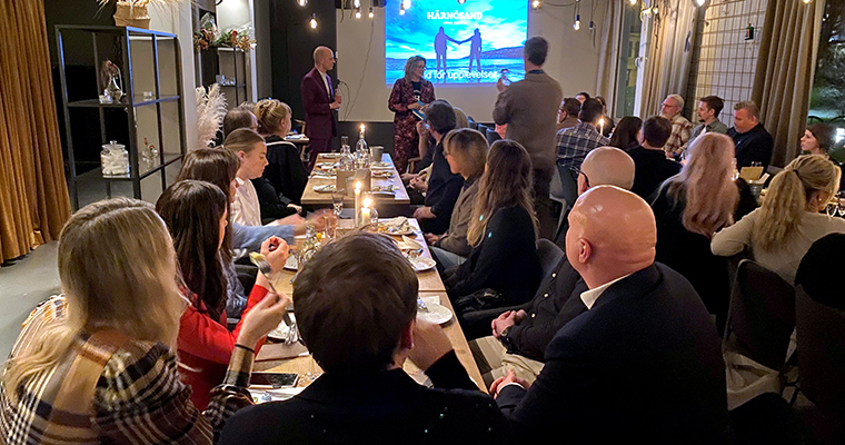 Många festklädda människor samlade framför scenen i en restauranglokal.