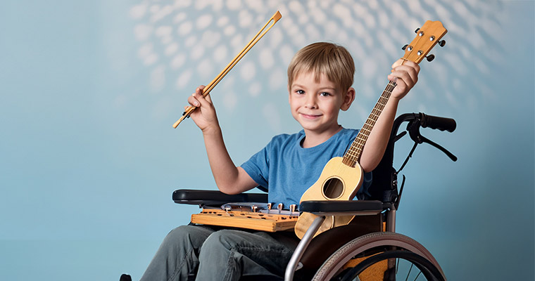 En pojke i rullstol håller en basgitarr.