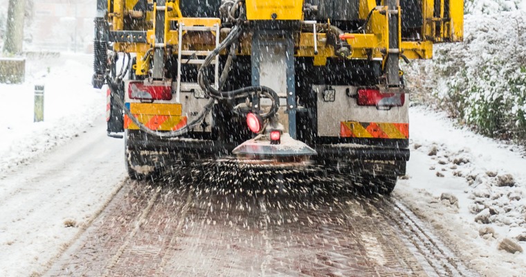 en gul lastbil med en saltspridare baktill