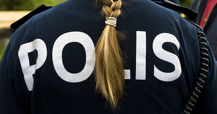 Ryggtavla på en oidentifierbar kvinnlig polis med fläta. Texten POLIS syns på ryggen.