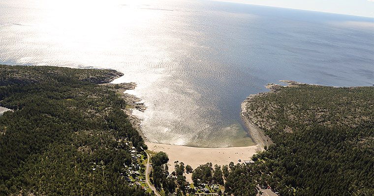 flygbild över en kuststräcka. I centrum syns en bred vik med en sandstrand.