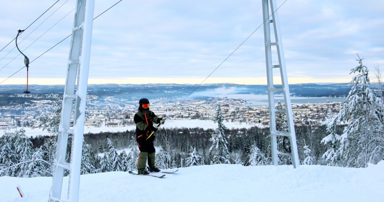 en skidåkare på väg upp i en lift med en vy över ett vinterlandskap i bakgrunden