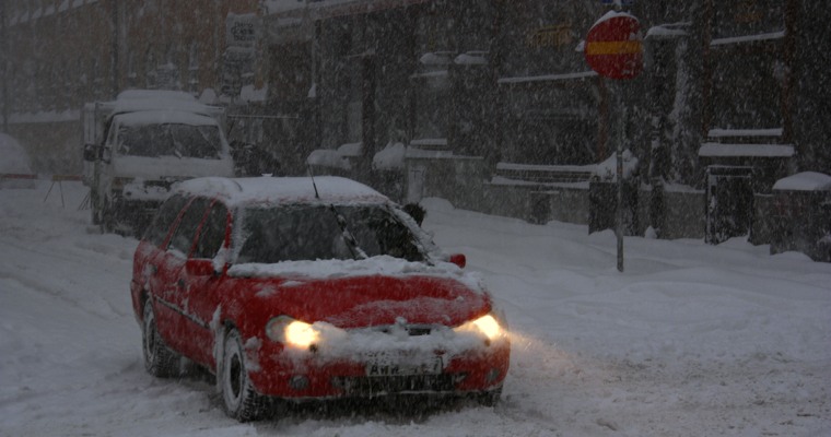 en röd bil i snöoväder i en gatumiljö med mycket snö