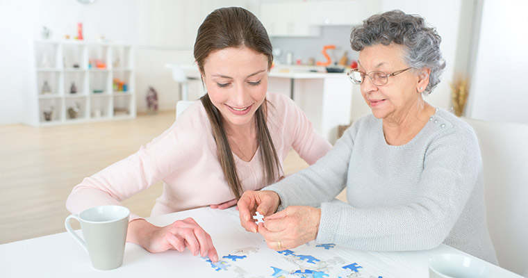 En ung flicka och en äldre kvinna som lägger pussel.
