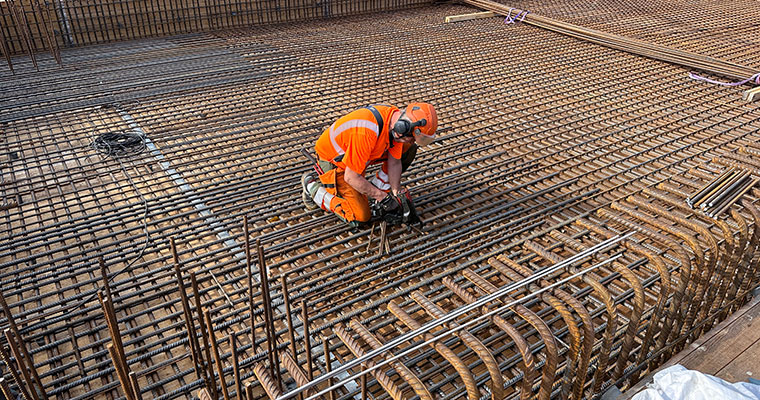 en person i arbetskläder jobbar med armeringsjärn på ett brobygge