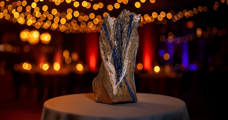 En prisstatyett står på ett bord. Statyetten är gjort i lera.