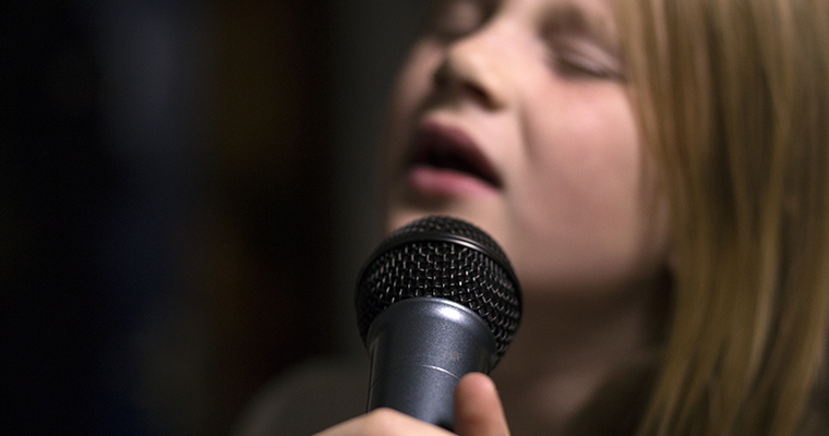 Barn som sjunger i en mikrofon