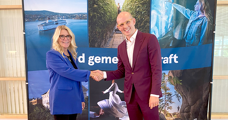 En man och en kvinna skakar leende hand.