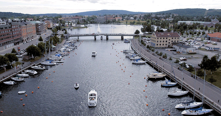 flygbild över ett sund genom en stad med båtar längs kajerna. En bro går över sundet.