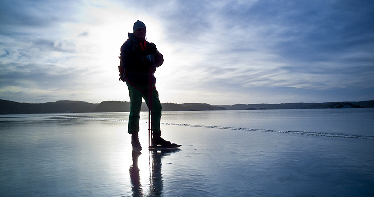 en person sedd bakifrån åker långfärdsskridskor på en stor blank is