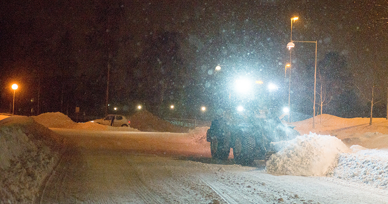 En hjullastare som plogar undan snö i mörkret.