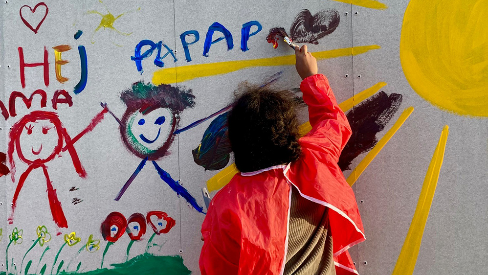 yngre person målar på stor vägg