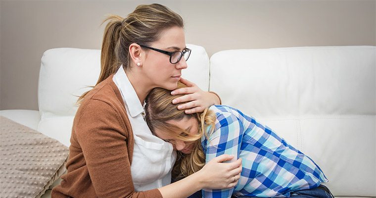 En mamma som tröstar sin dotter.