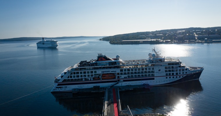 Två kryssningsfartyg i Härnösands hamn. Ett ligger vid kaj och ett är på väg in.