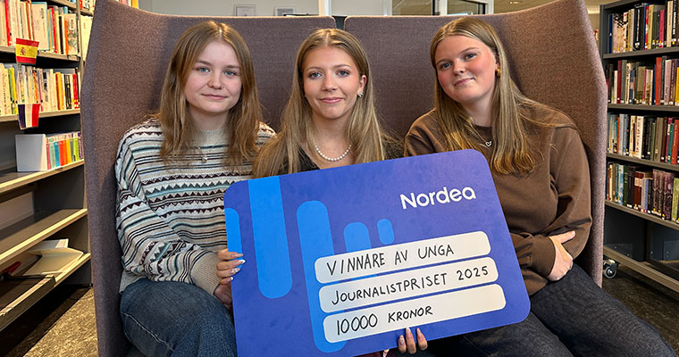 tre unga kvinnor sitter i en soffa med en stor prischeck i handen