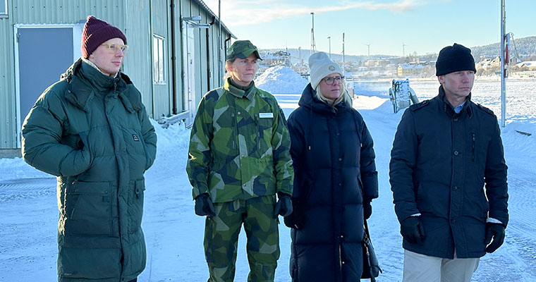 fyra personer står i en utemiljö