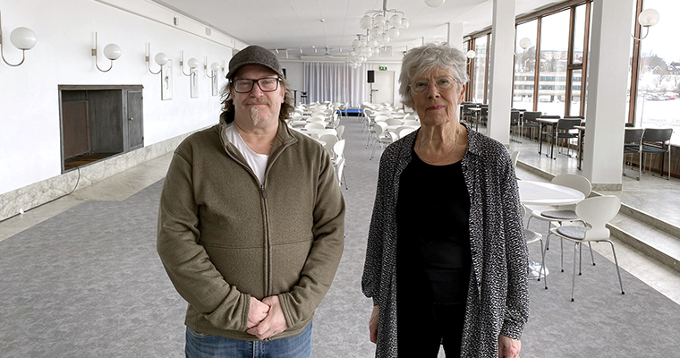 En man och en kvinna står bredvid varandra med ett stort tomt rum i bakgrunden.