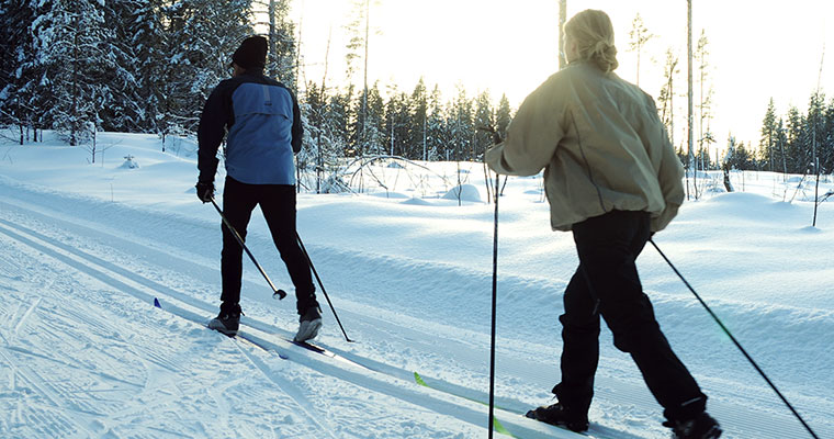 två skidåkare sedda bakifrån i ett skidspår