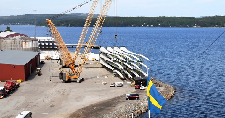 vy över en hamn med en kran och en hög med vindkraftsvingar