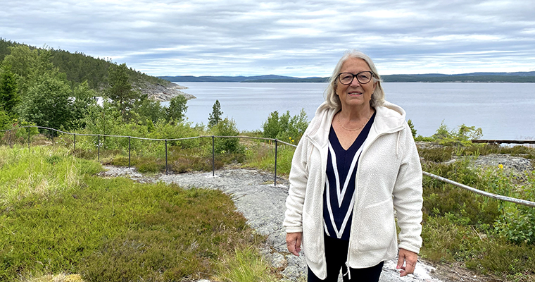 Kvinna står utomhus vid ett räcke med en vacker vy över havet.