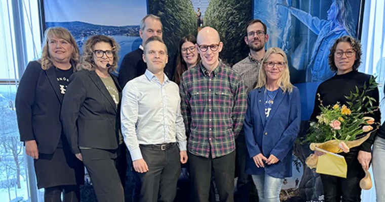 Gruppbild av ett tiotal glada människor på en scen.