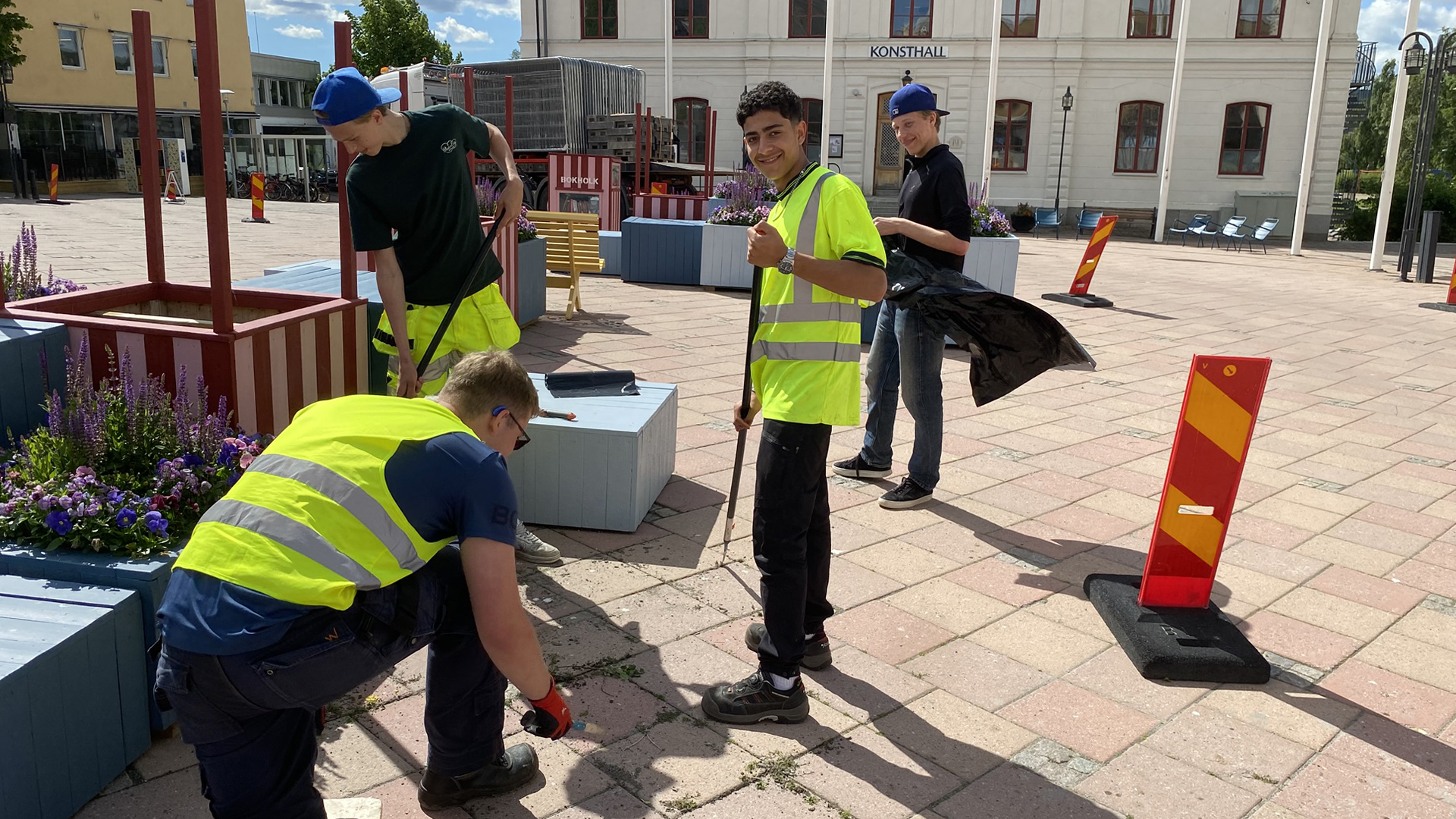 Fyra unga killar som, rensar ogräs på torget.