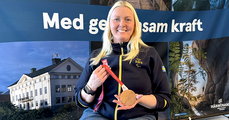 Glad kvinna visar upp en stort medalj.