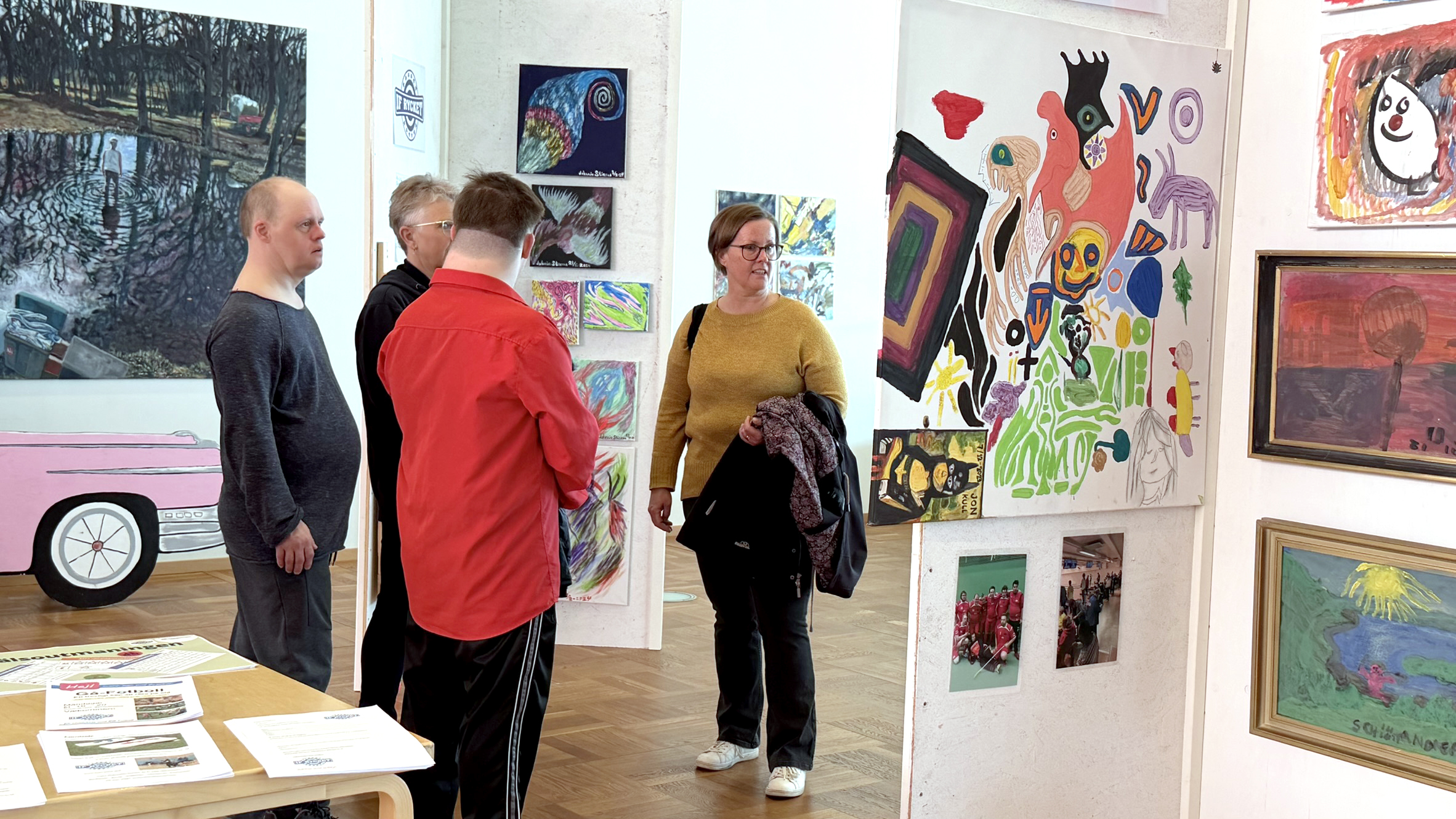 Människor vid utställningsskärmar där konstverk visas.