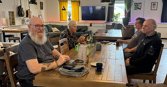Glada äldre personer sitter samlade runt ett långbord i ett fik.