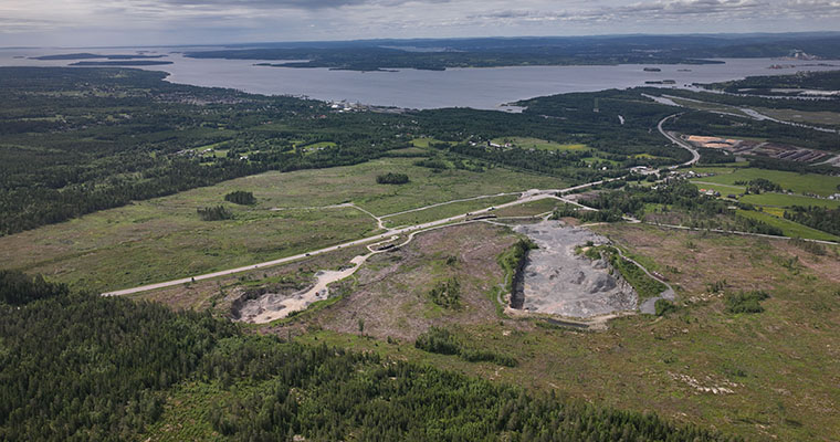 Flygbild över ett skogsområde med skog, vägar och en bergtäkt.