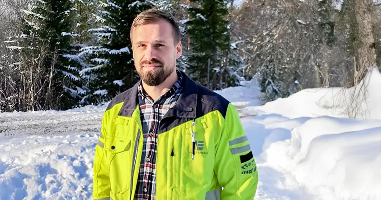 Morgan Rönnlund står i gul varseljacka, i bakgrunden ser man skog och snö. 