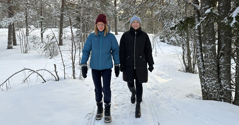 två personer går i skogen på vintern