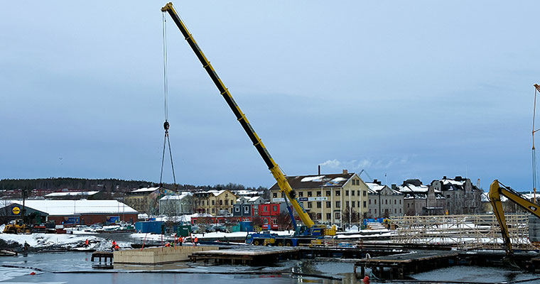 en stor kran lyfter en låda på plats i vattnet