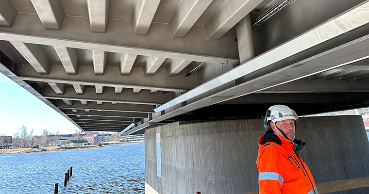 en man i arbetskläder under en stålbro.