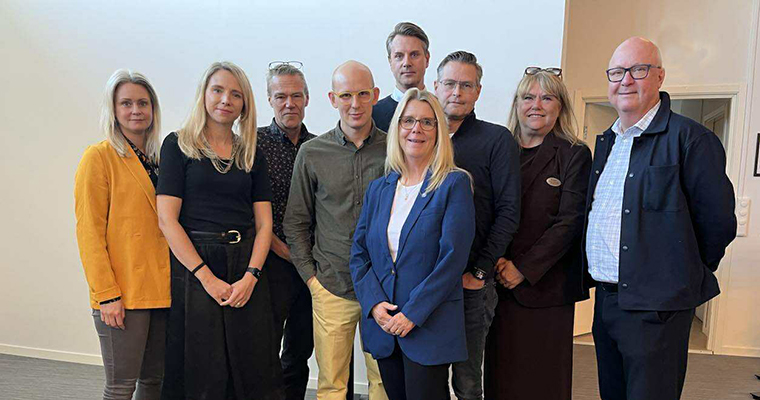 Gruppfoto med nio personer, män och kvinnor i olika åldrar.