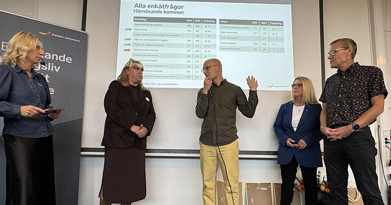 Flera personer diskuterar framför en filmduk som visar en tabell med siffror,