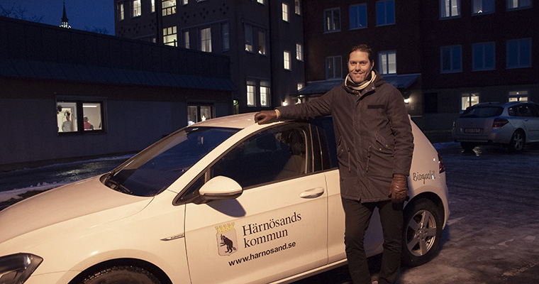 Människa framför bil med Härnösands kommuns logotyp på.