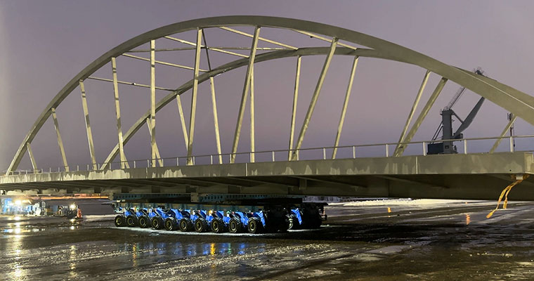 en stor bågbro står på en trailer med många tätt sittande hjul