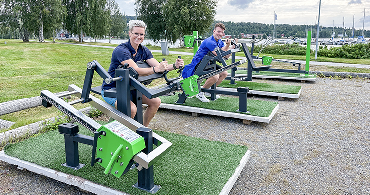 två personer tränaaar vid varsin maskin på ett utegym