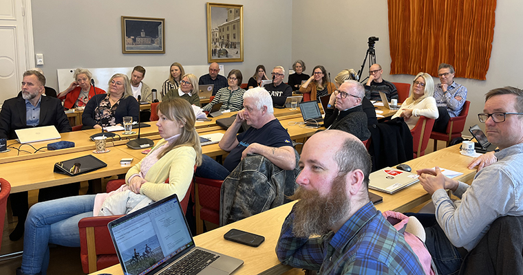 Ett tjugotal personer i ett mötesrum tittar på en talare utanför bild. 