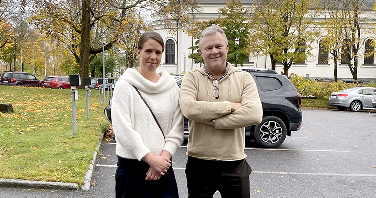 En man och en kvinna står utomhus på en parkering.