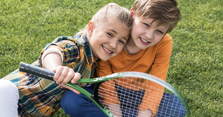 Två barn med ett tennisracket.