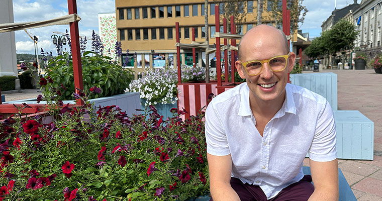 en man sitter bland blommor på ett torg