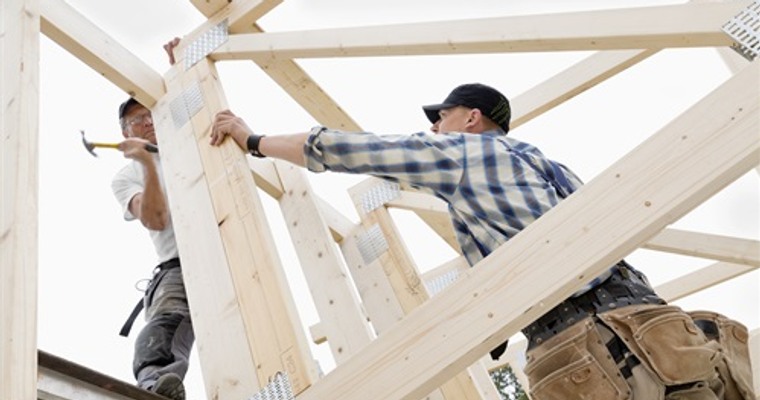 Modell av ett hus, en penna och en tumstock på en byggnadsritning