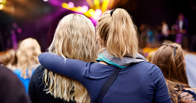 Två oidentifierbara tjejer tittar på en konsert.