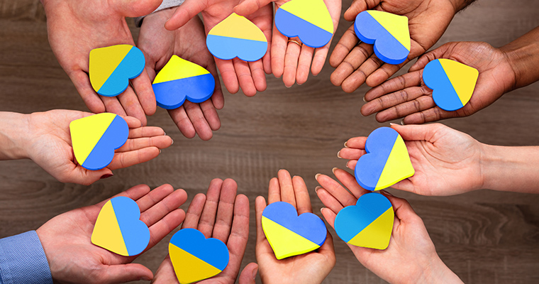 Händer som håller i varsitt hjärta i Ukrainas färger.